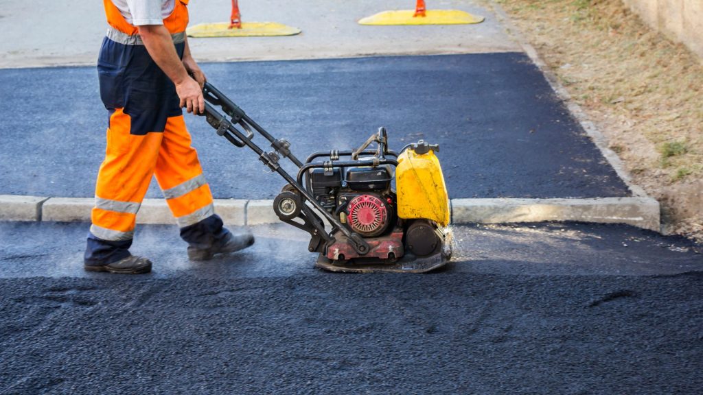 A worker using a machine on asphalt road